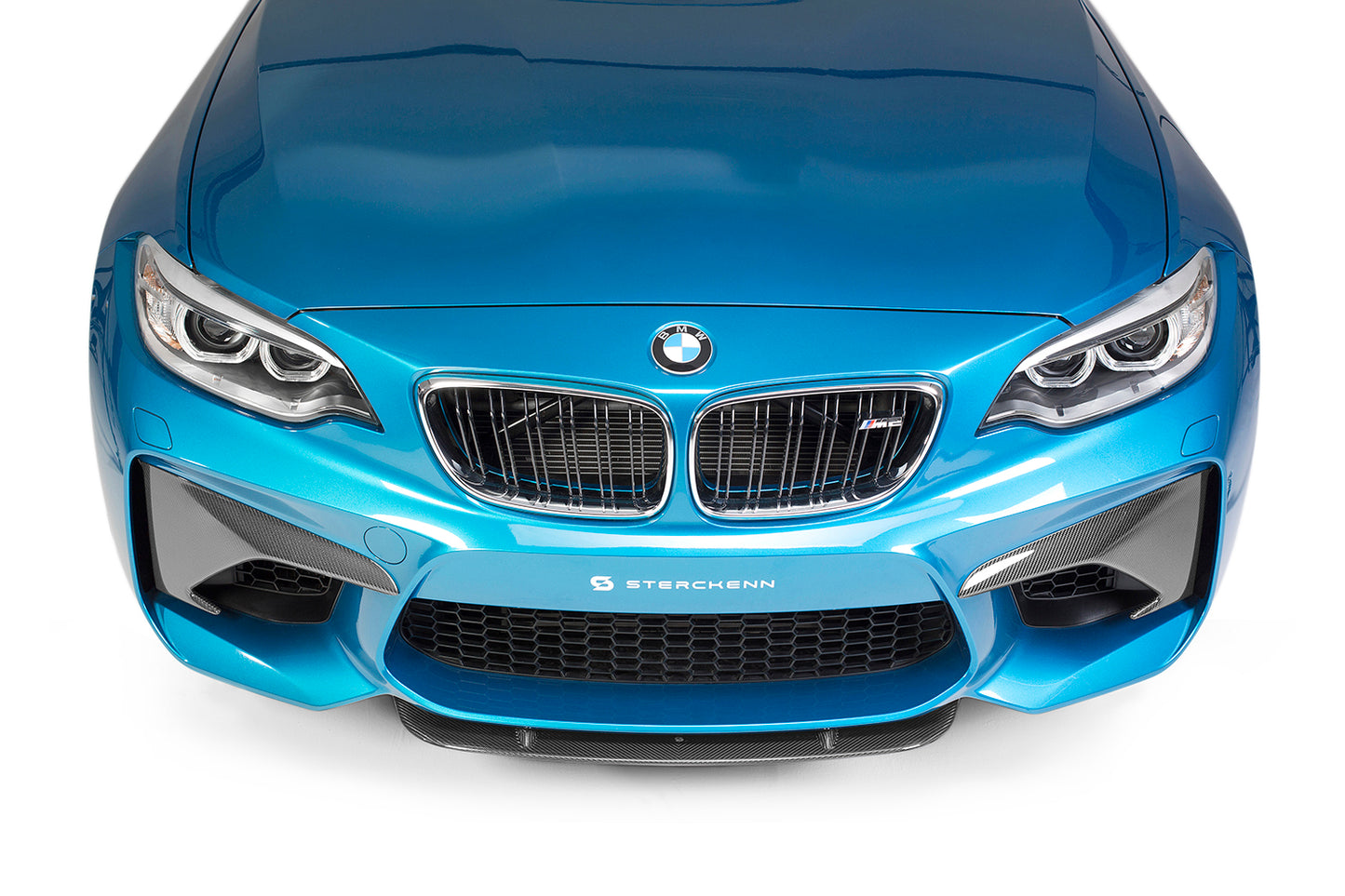 Top shot of the front bumper of a blue BMW M2 (F87) with a white background