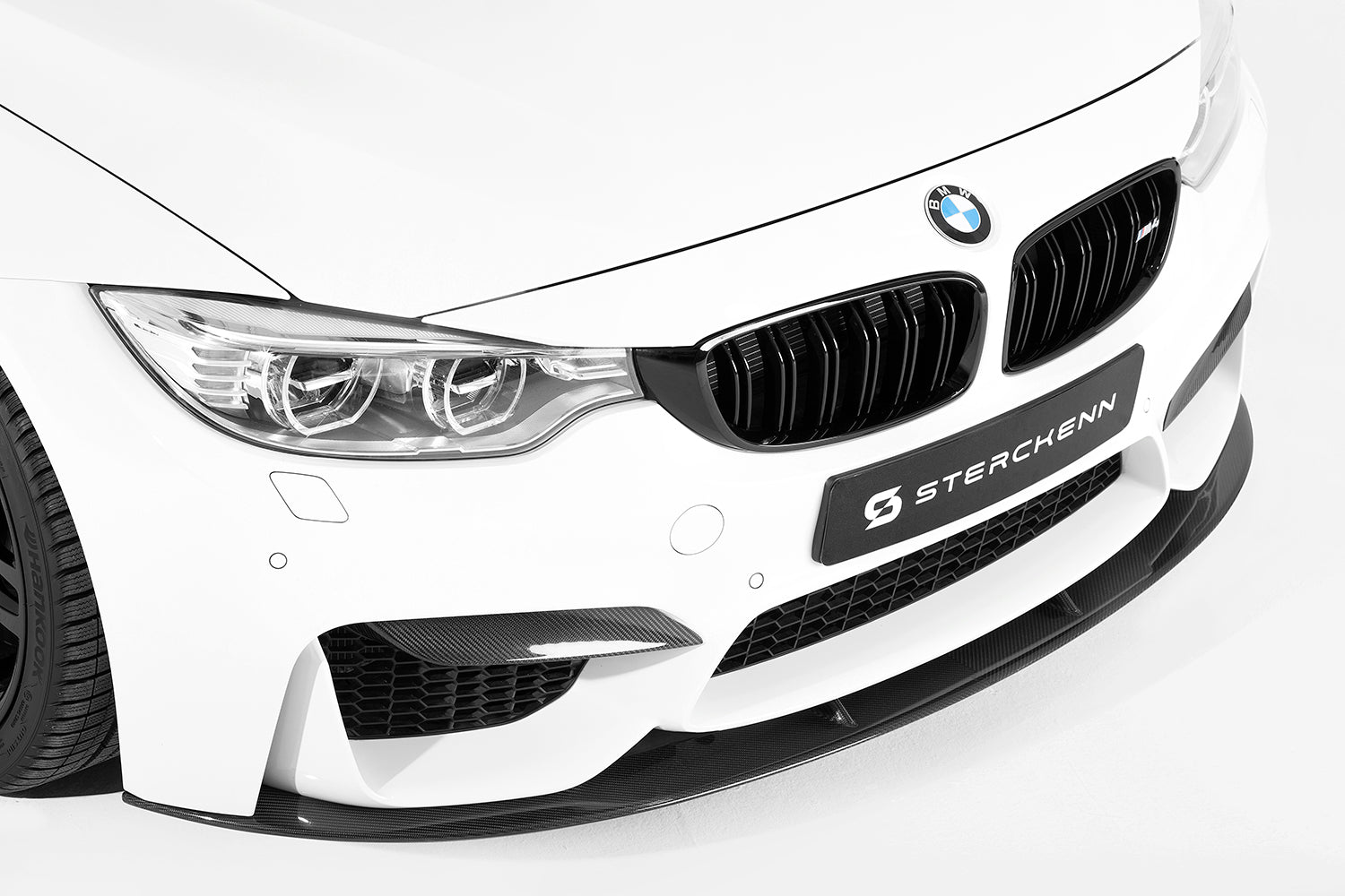 close-up on the front of the white bmw with the sterckenn logo