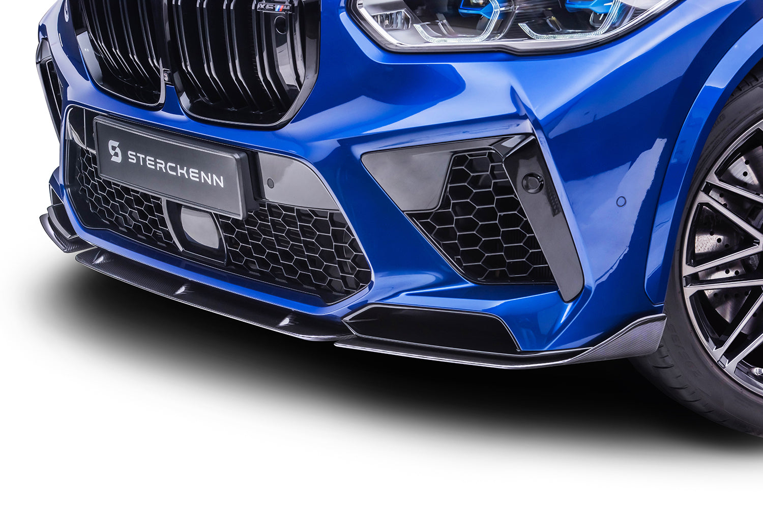 The front bumper of a blue BMW X5M (F95) on a white background