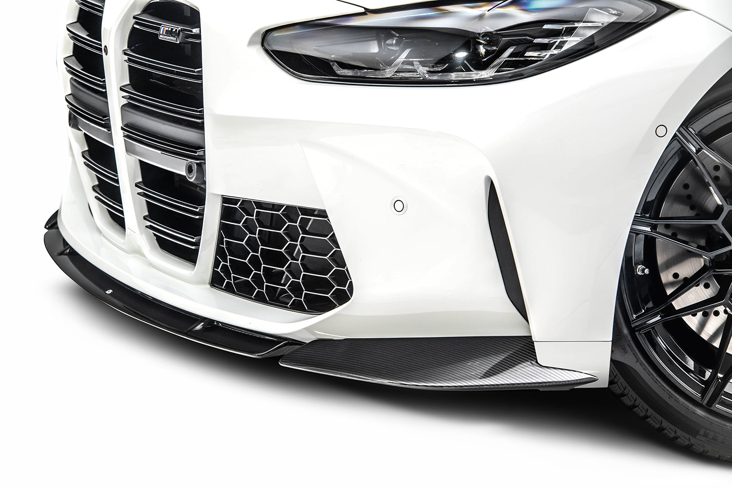 Close-up of the front bumper of a white BMW M4 (G82) on a white background